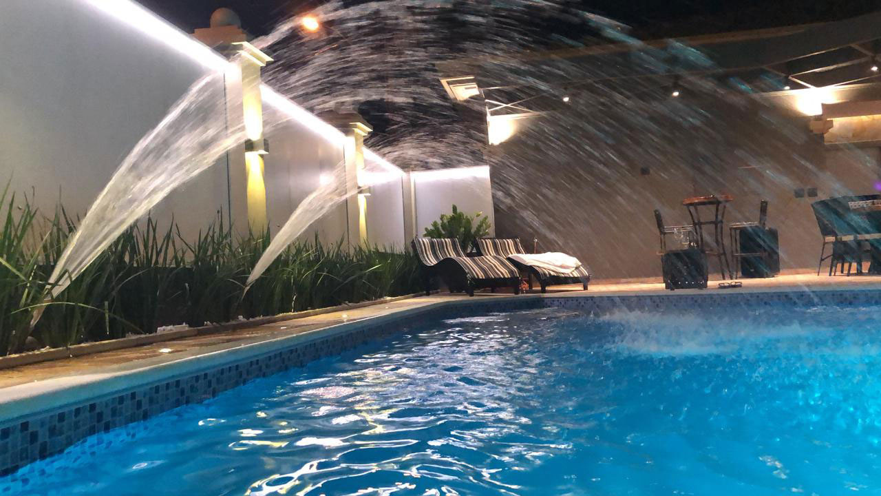 Área de lazer e piscina - Cascatas, iluminação embutida e vegetação criando um pátio de convívio que funciona à noite.