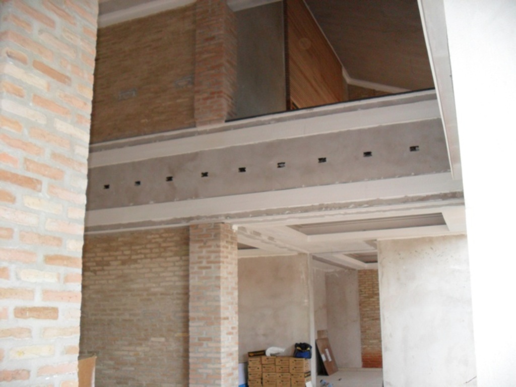 Pé-direito duplo em execução - Estrutura e alvenaria aparentes durante a obra, com mezanino e vigas expostas definindo a espacialidade.