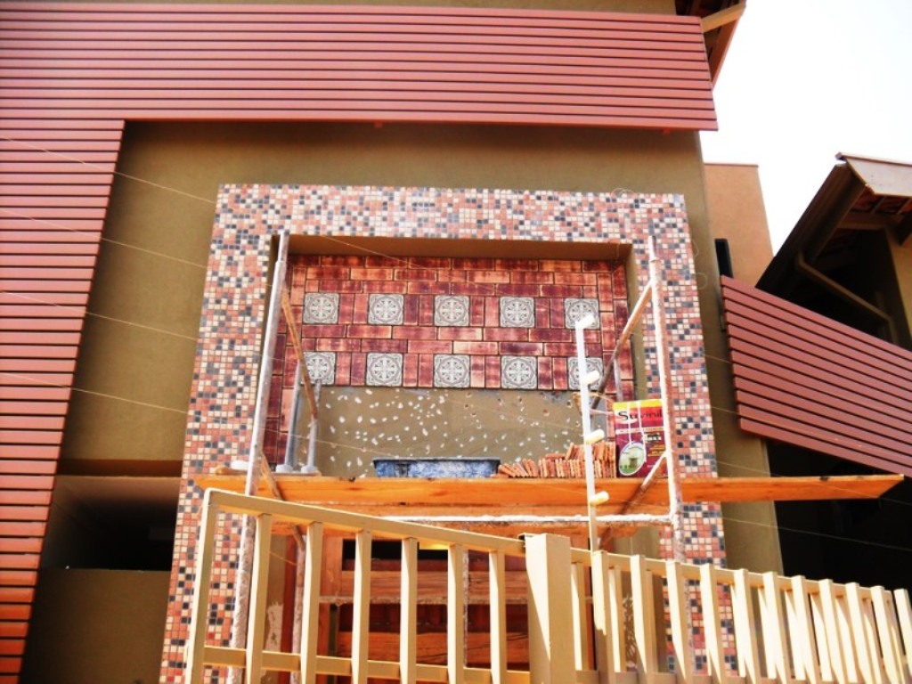 Detalhe de fachada em obra - Composição de pastilhas e ladrilhos sendo executada em fachada com brises horizontais.
