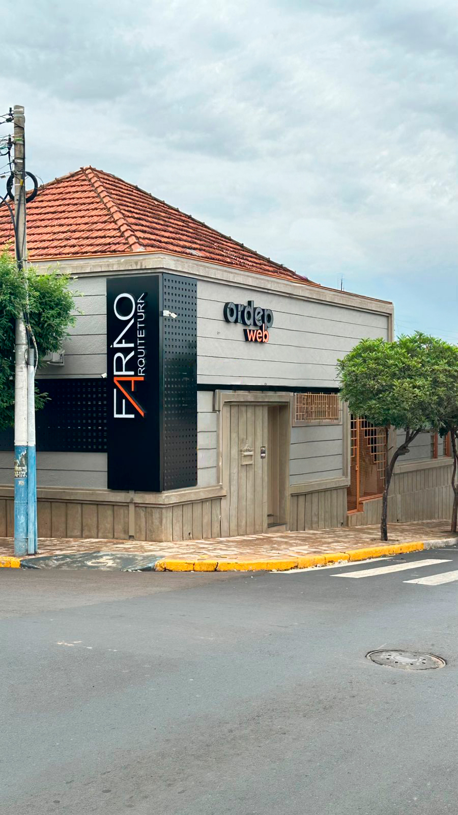 Fachada do escritório da Farão Arquitetura, com totem da marca na esquina, em Itajobi