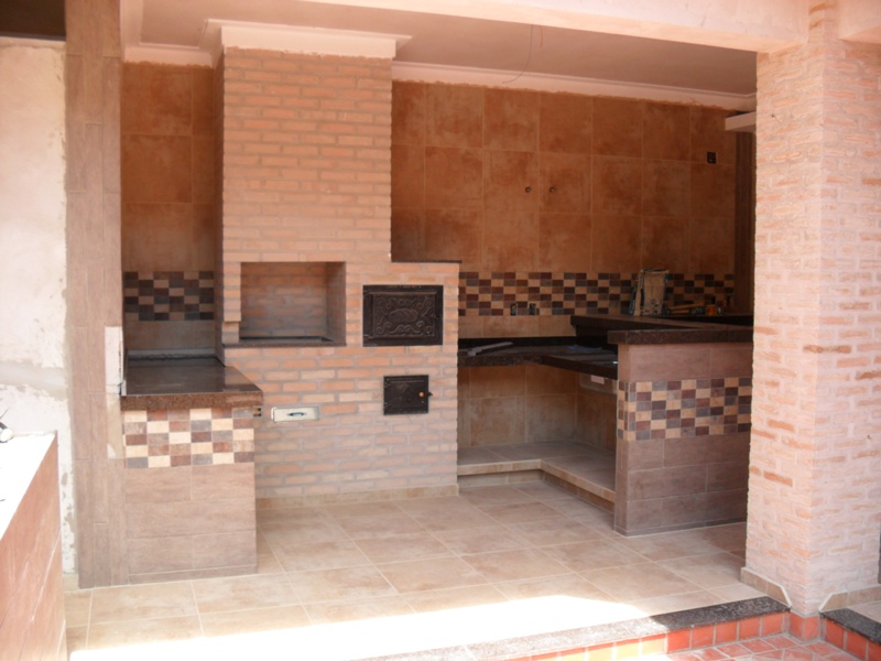 Espaço gourmet - Churrasqueira e forno em tijolo aparente, bancadas em granito e faixa de pastilhas percorrendo o ambiente.